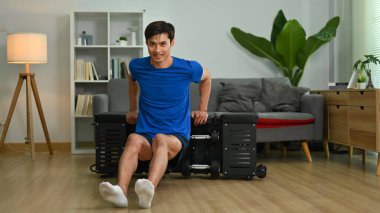 Full length of strong man exercising on sports bench at home. Home fitness and healthy lifestyle concept.