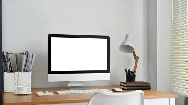 Blank computer screen, lamp and supplies on wooden desk. Empty screen for your advertising and creative design.