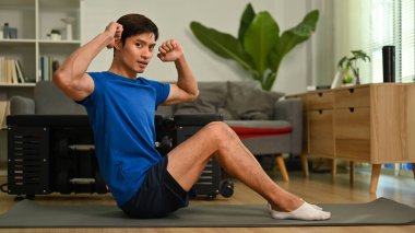 Sport man doing abs crunches exercise on mat in living room. Fitness, sport and healthy lifestyle concept.