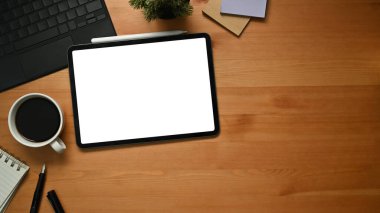 Digital tablet, cup of coffee and notepad on wooden table. Flat lay, Top view with copy space.