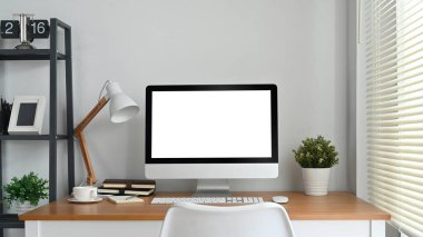 Modern home office interior with blank computer screen on wooden desk. Empty screen for your advertising and creative design.