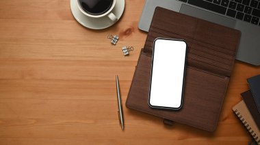 Wooden office desk with smart phone, leather personal organizer and laptop computer. Copy space for your text.