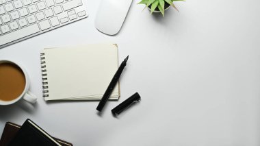 Flat lay, top view of blank notepad, cup of coffee, mouse and keyboard on white table. Copy space for your text.
