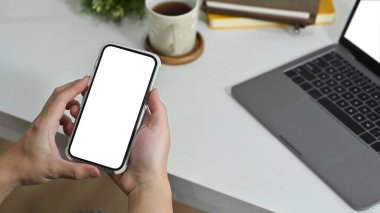 Man office worker using smart phone while sitting at his workplace. Blank screen for your advertise text.