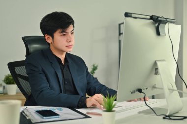 Young serious business man watching online webinar training or having virtual meeting video conference on computer screen.