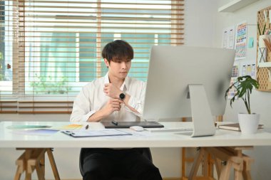 Handsome asian male website developer working on mobile application software design project at his workstation.