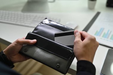Close up view of man holding plastic bank card and a black leather wallet. Finance, loan, savings concept.