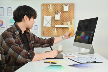 Side view of young man UX graphic designer working together for mobile application software design project at workstation.