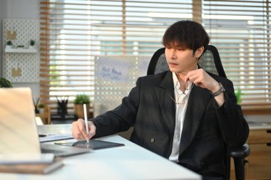 Attractive man corporate CEO in elegant suit watching online presentation on laptop screen at his workstation.