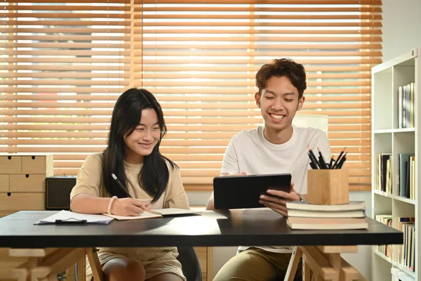 Smiling asian male private tutor helping young student with homework. Tutorial and educational concept.