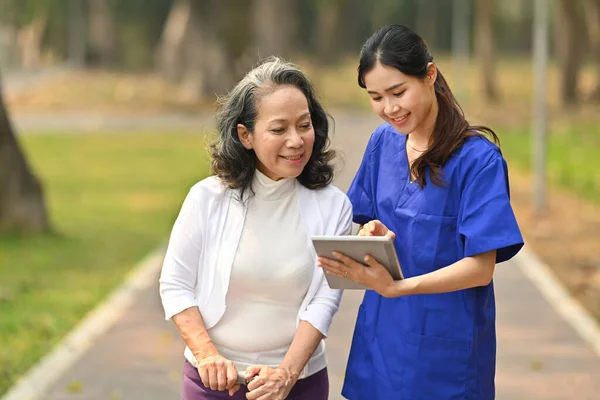 Dijital Tablet Tutan Ilgili Hemşire Rehabilitasyon Merkezindeki Yaşlı Kadına Profesyonel — Stok fotoğraf