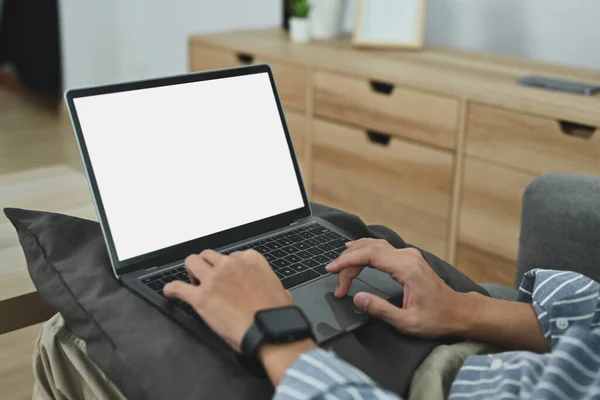Close up view of man typing on laptop computer with blank white screen. Distance online study and freelance work concept.