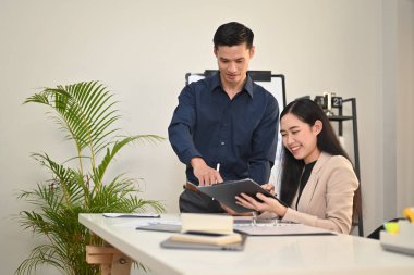 Yakışıklı Asyalı erkek yönetici, dijital tablet hakkındaki bilgileri modern kurumsal ofisteki meslektaşlarına anlatıyor..