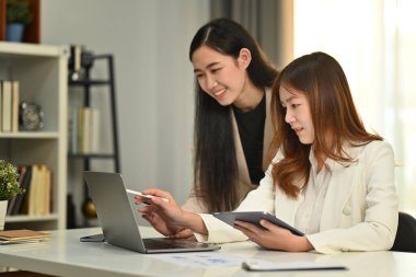 Gülümseyen iş arkadaşları iş birliği yapıyor, şirket toplantısı sırasında yeni pazarlama üzerine beyin fırtınası yapıyorlar..