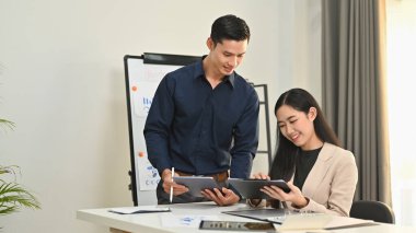 Gülümseyen Asyalı işadamı, şirket toplantısında iş arkadaşlarıyla fikir alışverişinde bulundu..