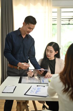 Asyalı erkek yönetici iş stratejisini paylaşıyor, toplantıda iş arkadaşlarıyla mali verileri tartışıyor.