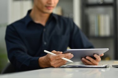 Seçici olarak ellere odaklan. Stylus kalem tutan ve ofis masasında dijital tablet kullanan işadamının kırpılmış görüntüsü.