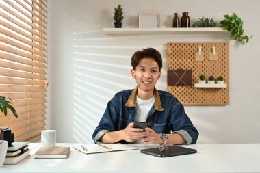 Kot ceket giyen yakışıklı bir adamın portresi güneşli, şık bir ofis içinde çalışıyor..