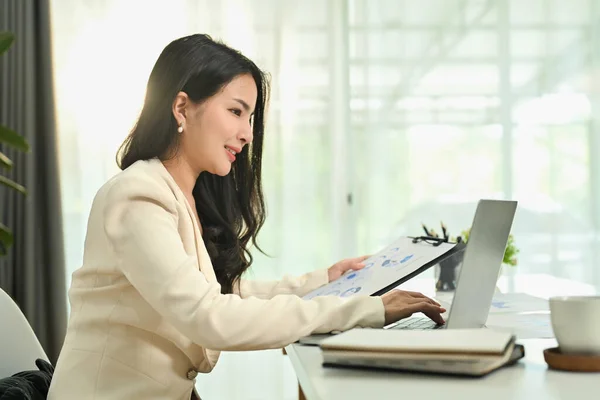 アジアの女性マネージャーは会計文書を保持し ラップトップでオフィスで働く財務データをチェックする — ストック写真