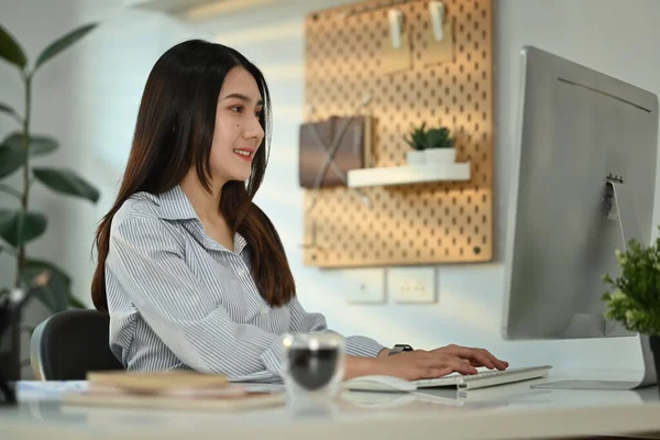 彼女のオフィスでオンラインウェブセミナーを見てコンピュータモニターを見て満足中小企業起業家 — ストック写真