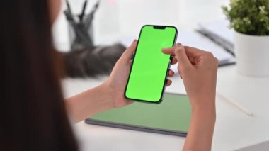 Genç bayan ofis çalışanının omuzlarının üstünden yeşil ekran leke telefonuna kayıyor..