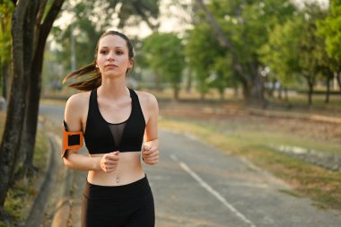 Spor giyimli atletik kadın akşamları tropikal parkta koşuyor. Fitness, eğitim ve sağlıklı yaşam tarzı konsepti.
