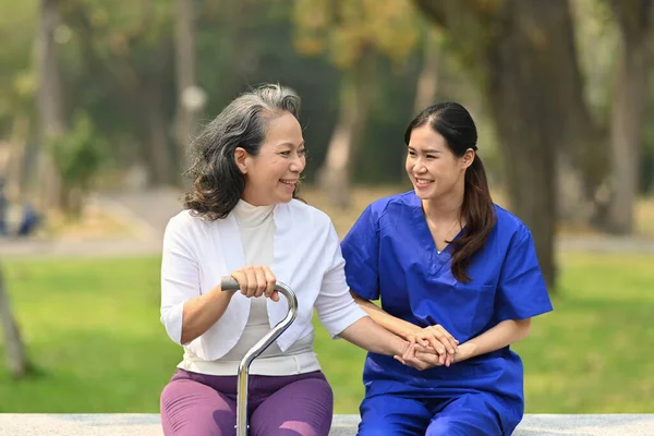 Gülümseyen Asyalı Kadın Hemşire Yaşlı Kadının Elini Tutuyor Dışarıda Rehabilitasyon — Stok fotoğraf