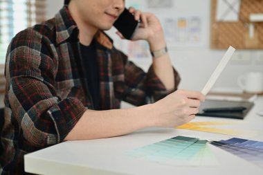 Dahili tasarımcının müşteriyle cep telefonu konuşması ve ofis binası için renk seçimi..