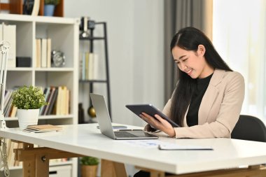 Modern ofiste finansal ve pazarlama projeleri üzerinde çalışan dijital tablet kullanan şık güzel yöneticinin portresi.