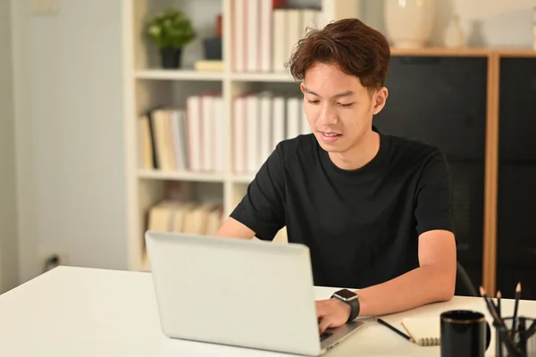 Smiling young asian man watching webinar or training course on laptop. Freelance, distance, education, e-learning concept.