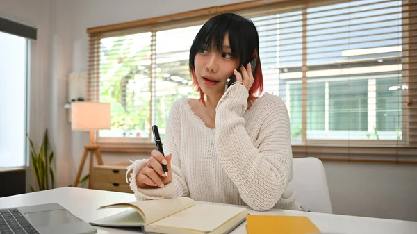 Urocza Młoda Azjatka Freelancer Mając Rozmowę Telefoniczną Notatki Notatniku — Zdjęcie stockowe