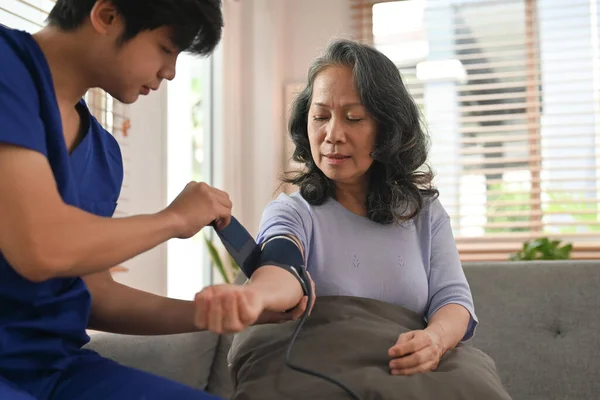 stock image Health visitor measuring blood pressure senior woman at home. Elderly healthcare and Home health care service concept.