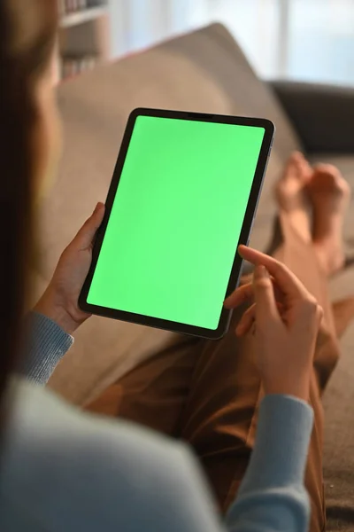 stock image Close up view of casual young woman using digital tablet on couch at home. Green screen for montage your graphic display.