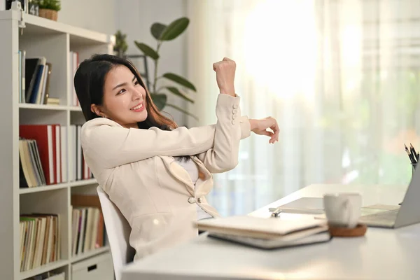 満足アジアの女性ストレッチ腕取り休憩で仕事で快適な椅子で現代のホームオフィス — ストック写真