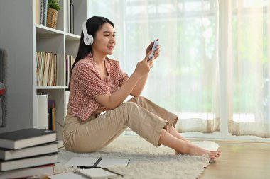 Cep telefonu kullanan, müzik dinleyen, podcast ya da kablosuz kulaklık kullanan hoş bir genç kadın..