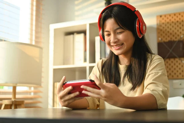 Radosna Nastoletnia Azjatka Słuchawkach Grająca Gry Wideo Przenośnej Konsoli Gier — Zdjęcie stockowe