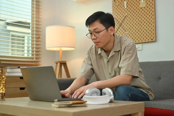 Fiatal Ázsiai Férfi Kanapén Laptopot Használ Szabadúszó Távmunka Learning Koncepció — Stock Fotó