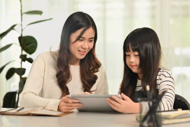 Ev ödevi yapan sevimli liseli kız ya da evde annesiyle internetten öğreniyor. Evde eğitim, öğrenim ve aile kavramı.