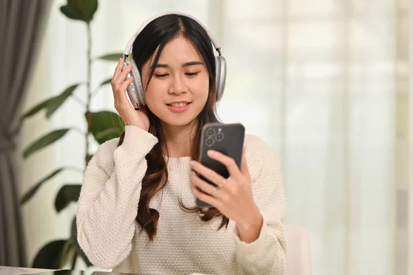 Szczęśliwa Młoda Kobieta Nosząca Słuchawki Bezprzewodowe Korzystająca Telefonu Komórkowego Salonie — Zdjęcie stockowe