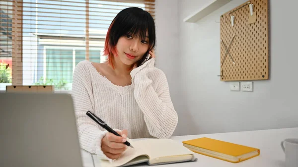 漂亮的亚洲女人 在家里的办公室里一边打电话一边用手提电脑 — 图库照片