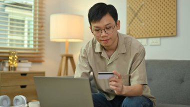 Kredi kartı tutan ve bilgisayarla internet bankacılığı yapan hoş bir adam. İnternetten alışveriş, e-ticaret..