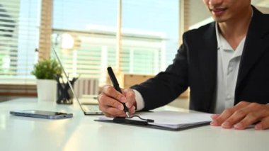 Profesyonel genç işadamı pazar araştırması sonuçlarını okuyor ve yazıyor, modern işyerinde çalışıyor..