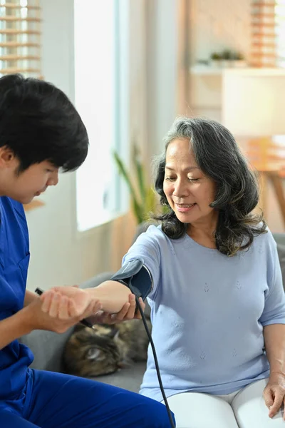 男性介護者は血圧計で血圧中年女性をチェックします 在宅医療サービスの概念 — ストック写真