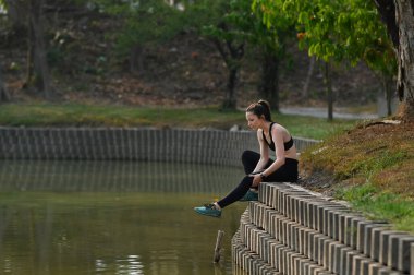 Parktaki antrenmandan sonra güzel güneş ışığıyla dinlenen atletik bir kadın. Sağlıklı yaşam tarzı kavramı.