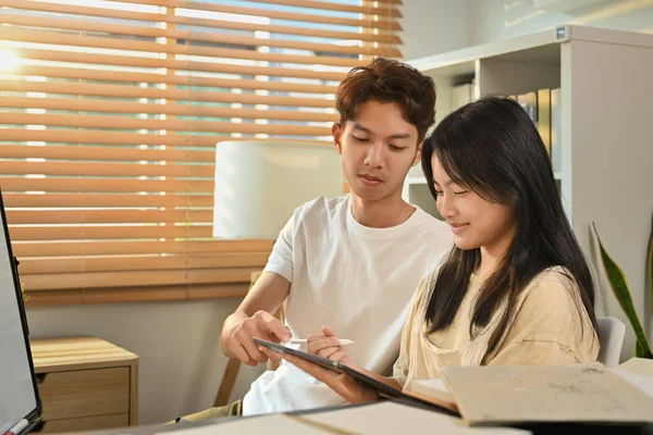 Image of tutor giving private educational lesson to teenage asian girl. Homeschooling and education concept.