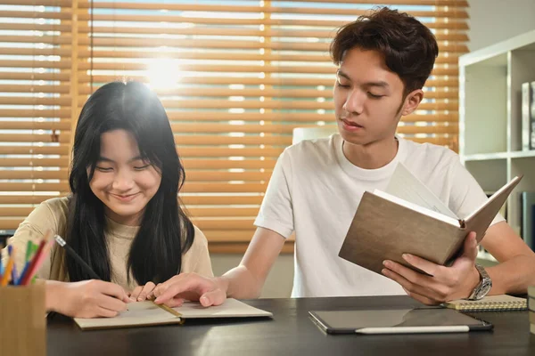 stock image Tutor helping teenage asian girl doing assignments, giving private educational lesson at home.