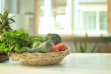 Modern mutfakta beyaz masada çeşitli sağlıklı organik sebzelerle dolu bir sepet. Sağlıklı gıda ve vejetaryen konsepti.