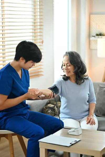 高齢患者の血圧を測定する若いアジア系男性医療従事者 医療の概念 — ストック写真