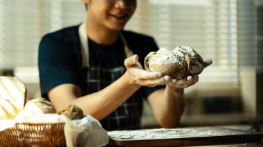 Erkek fırıncı elinde taze pişmiş ekşi ekmek tutuyor. Sağlıklı beslenme ve geleneksel fırın ve pasta konsepti.