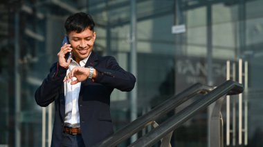 Milenyum işadamı ofis binasının önünde otururken akıllı telefon kullanıyor. Modern yaşam tarzı ve teknoloji kavramı.